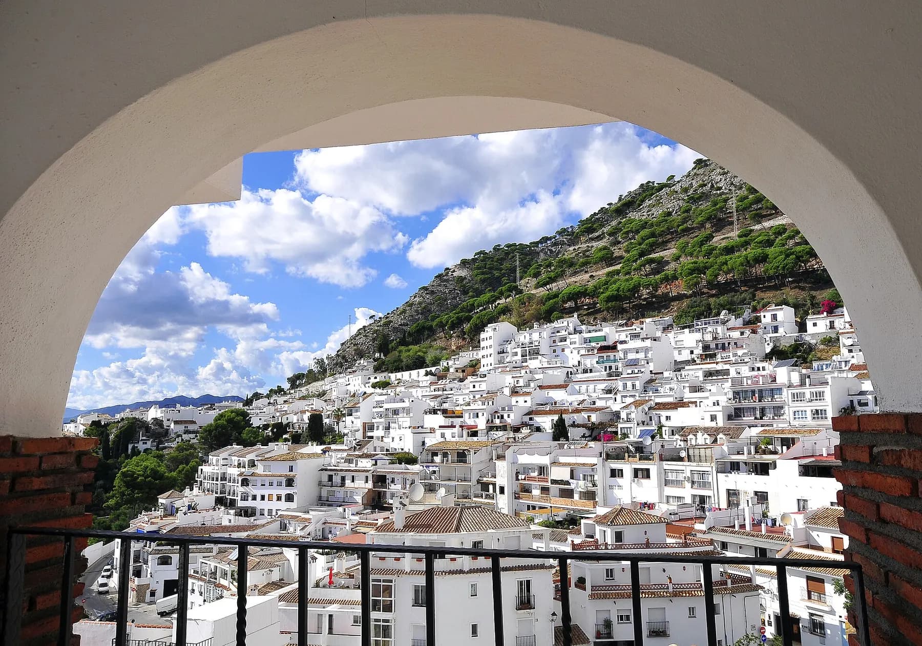 White houses of Mijas Pueblo on the Sierra de Mijas, seen through an arch of the old town wall